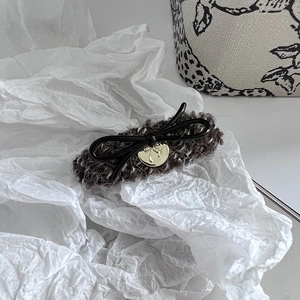 Detailaufnahme der braunen Plüsch-Haarspange mit schwarzer Schleife und Herzanhänger