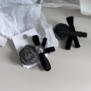 Detail of silver camellia flower and black velvet bow hair clips on display card