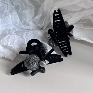 Detail of elegant black velvet hair claw clip with grey camellia and silver bead accents