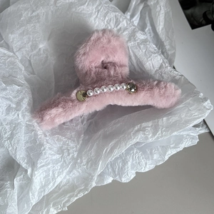 Détail de la pince à cheveux en fausse fourrure rose avec perles et strass brillants