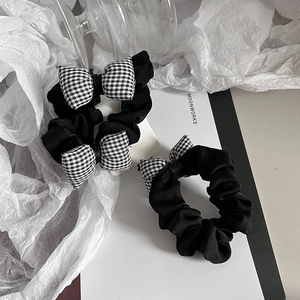 Détail de deux chouchous minimalistes en tissu avec des nœuds à carreaux noirs et blancs