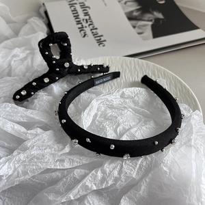 Detail of handmade black fabric headband with pearls and rhinestones on white surface