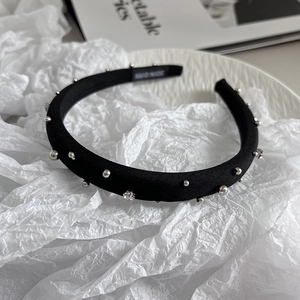 Detail of handmade black fabric headband with silver beads and rhinestones on ceramic