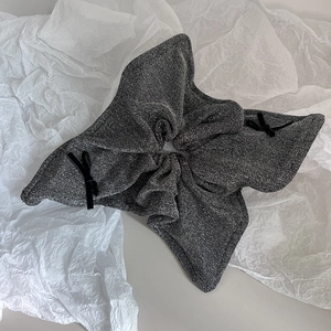 Close-up of silver-grey shimmering scrunchie with delicate black bow details and texture