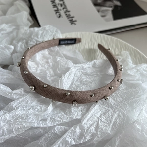 Close-up of a handmade brown fabric headband with silver beads and rhinestones detail