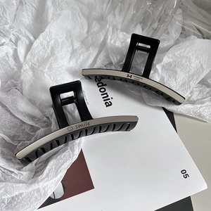 Close-up of minimalist black matte hair claws with silver metal letter engravings