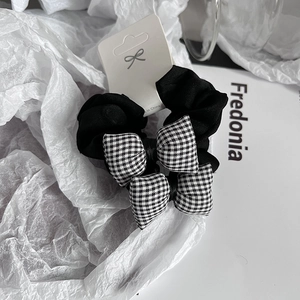 Lot de deux chouchous noirs en tissu avec nœuds à carreaux noir et blanc sur papier