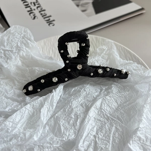 Detail of elegant black fabric hair claw clip with hand-sewn pearls and rhinestones