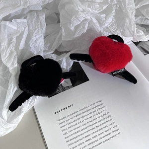 Détail de pinces à cheveux en peluche en forme de cœur rouge et noir avec étiquette
