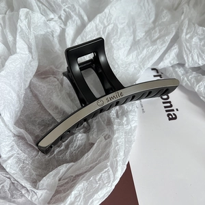 Close-up of matte black large hair claw clip with silver metal 'smile' engraving