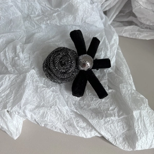 Detailed shot of black fabric rose and silver matte sphere on a handcrafted hair clip