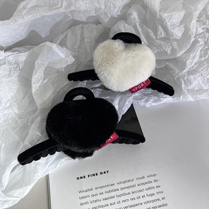 Détail de pinces à cheveux coeur en peluche noir et blanc cassé avec étiquette sport