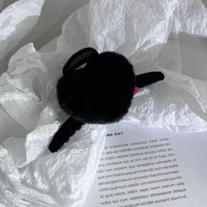 Gros plan de la pince à cheveux en peluche noire sur papier blanc texturé