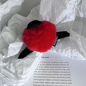 Vue détaillée d'une pince à cheveux en peluche rouge avec oreilles noires et étiquette mode