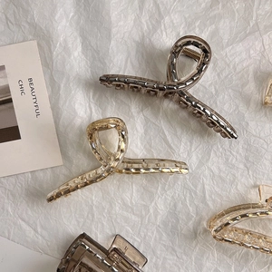 Detailed view of two elegant geometric crystal hair claws in amber and champagne tones