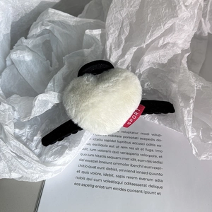 Détail de la pince à cheveux cœur en peluche crème avec étiquette sport et base noire
