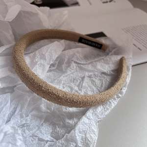 Detail of light khaki knit fabric headband with handmade label on white paper background