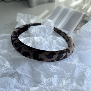Detailed view of winter leopard print headband with soft fabric texture on tissue paper