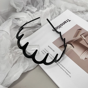 Close-up of black wavy headband with teeth on a white magazine and fabric background