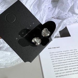 Vue rapprochée de pinces en cristal K9 en forme de cœur sur carte noire et papier froissé