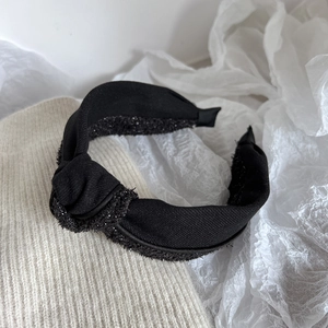 Close-up of black knot headband featuring textured fabric and sparkling silver details