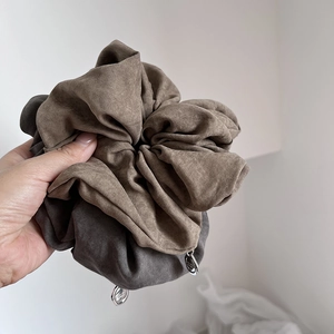 Macro shot of large coffee and grey scrunchies with elegant silver metal charms