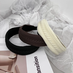Détail de serre-têtes en maille torsadée en noir, marron et beige, texture douce