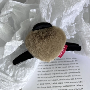Détail d'une pince à cheveux cœur en peluche marron café avec étiquette Sport et base mate