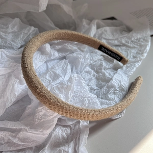 Detail of khaki knit fabric headband with high crown design and handmade woven label