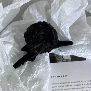 Détail de la pince à cheveux noire en peluche avec tissu en velours sur papier blanc