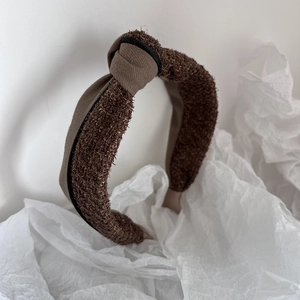 Close-up of brown knot headband featuring tweed fabric texture on white background