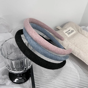 Three minimalist sponge headbands in pink, blue, and black colors on a neutral background
