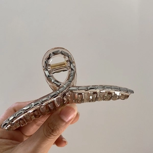Close-up of large resin hair claw clip with grey rhinestones and golden spring detail