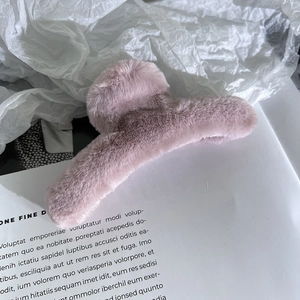 Dettaglio ravvicinato di una pinza per capelli in peluche rosa con morbida ecopelliccia