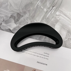 Détail d'une pince à cheveux noir mat en forme de croissant au design évidé