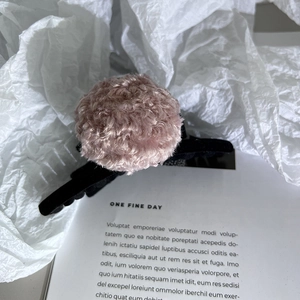 Vue détaillée de la pince à cheveux noire avec décoration pompon en fourrure mauve