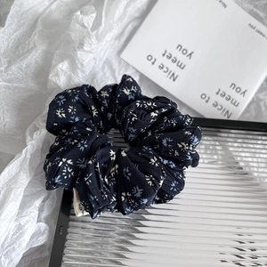 Detailed close-up of dark blue floral scrunchie with soft fabric folds and delicate prints