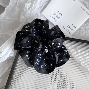 Close-up of floral scrunchie with dark blue flower patterns and black satin trim edges