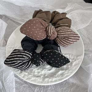 Detailed view of handmade bow scrunchies with polka dots and stripes in a white ceramic dish