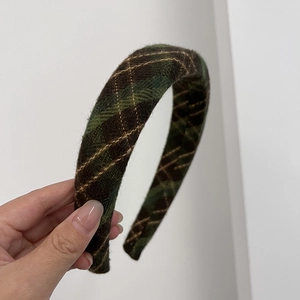 Close-up of retro plaid headband with dark green fabric and gold stitching detail