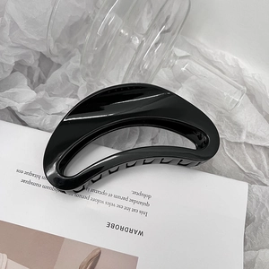 Détail d'une pince à cheveux noire brillante avec un design en croissant creux