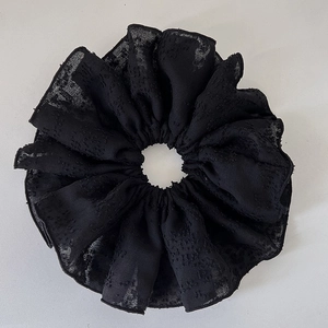 Gros plan d'un chouchou en mousseline noire avec une texture gaufrée élégante et un tissu doux