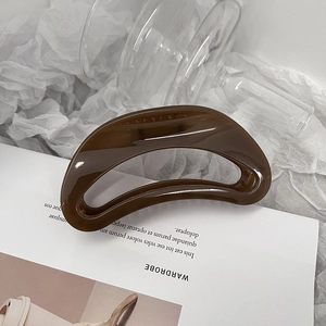 Gros plan d'une grande pince à cheveux en forme de croissant ambre sur fond esthétique