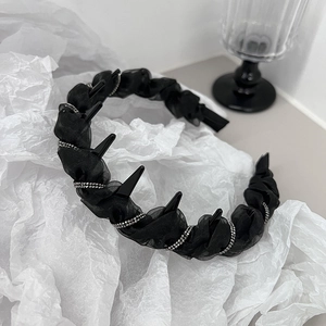 Detail of black pleated headband featuring silver rhinestones and punk style spikes