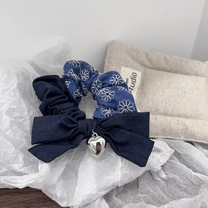 Detail of blue denim bow hair tie with silver heart charm and floral embroidery scrunchie