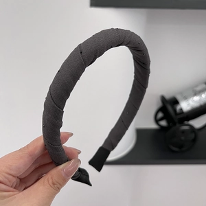 Close-up of a dark grey fabric headband with subtle black bead accents and comfortable ends