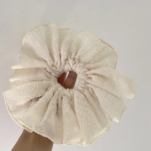 Gros plan du chouchou beige surdimensionné montrant la broderie et la texture du tissu