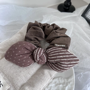 Detail of vintage brown hair scrunchie with polka dot and striped bow tie on ceramic tray