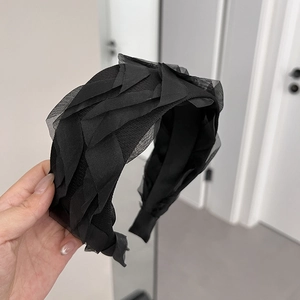 Detail of multi-layered black mesh headband featuring elegant pleated tulle fabric