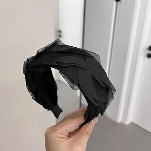 Detailed macro view of layered black mesh pleats on an elegant vintage lace headband